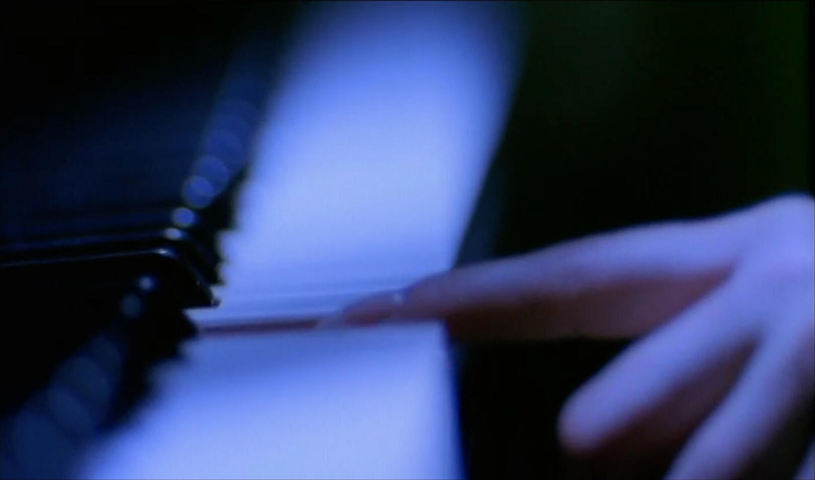 Handheld lens in front of camera, extreme short depth of field - Image finger striking piano key in cool light