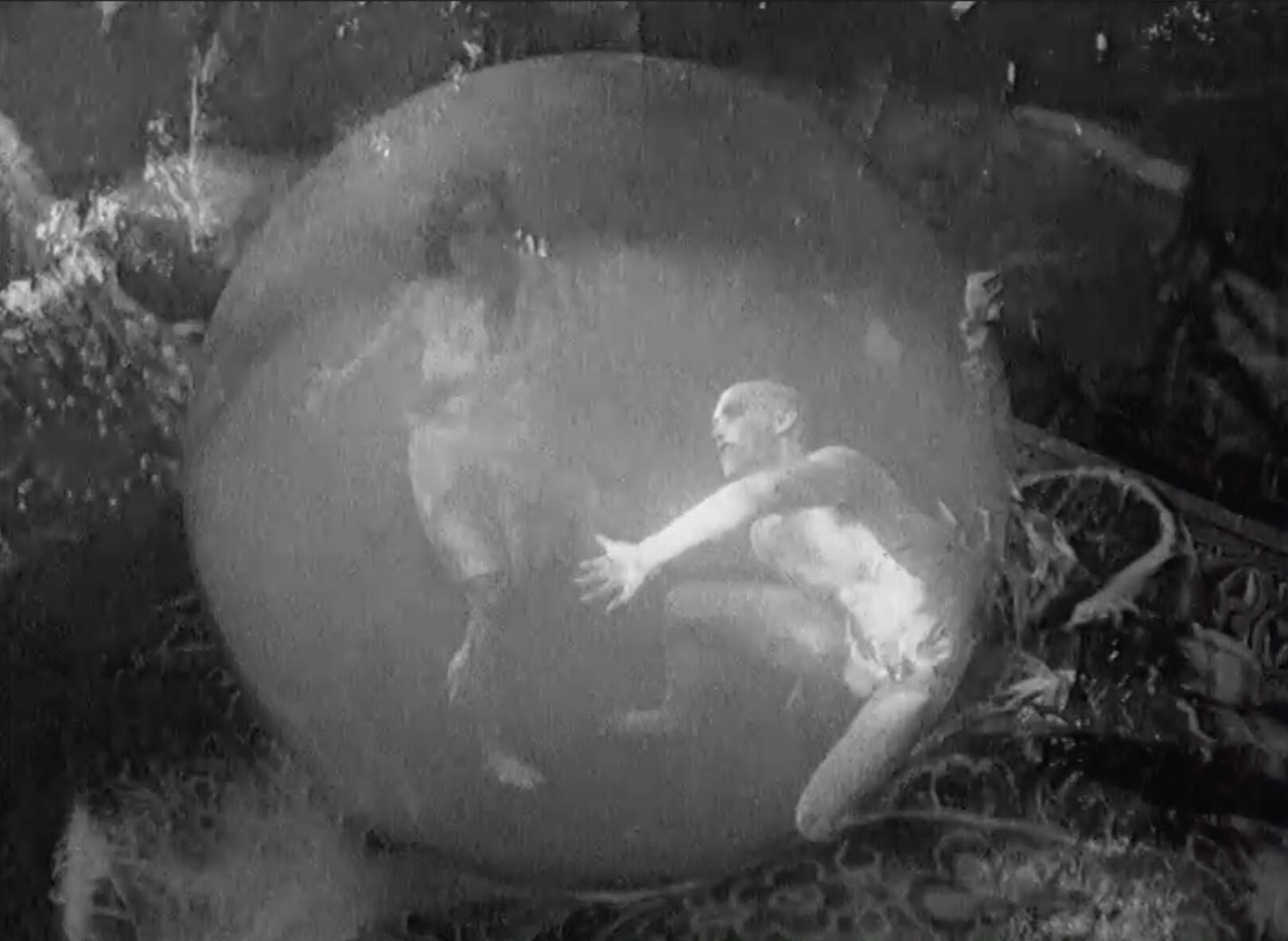 Black & White image of ghostlike dancers in crystal ball, shot with hand crank camera from 1920's silent period film