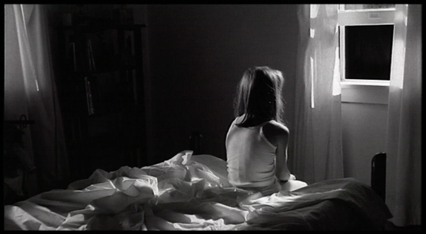 Black & White handcrank silent film frame of a girl looking out window at night