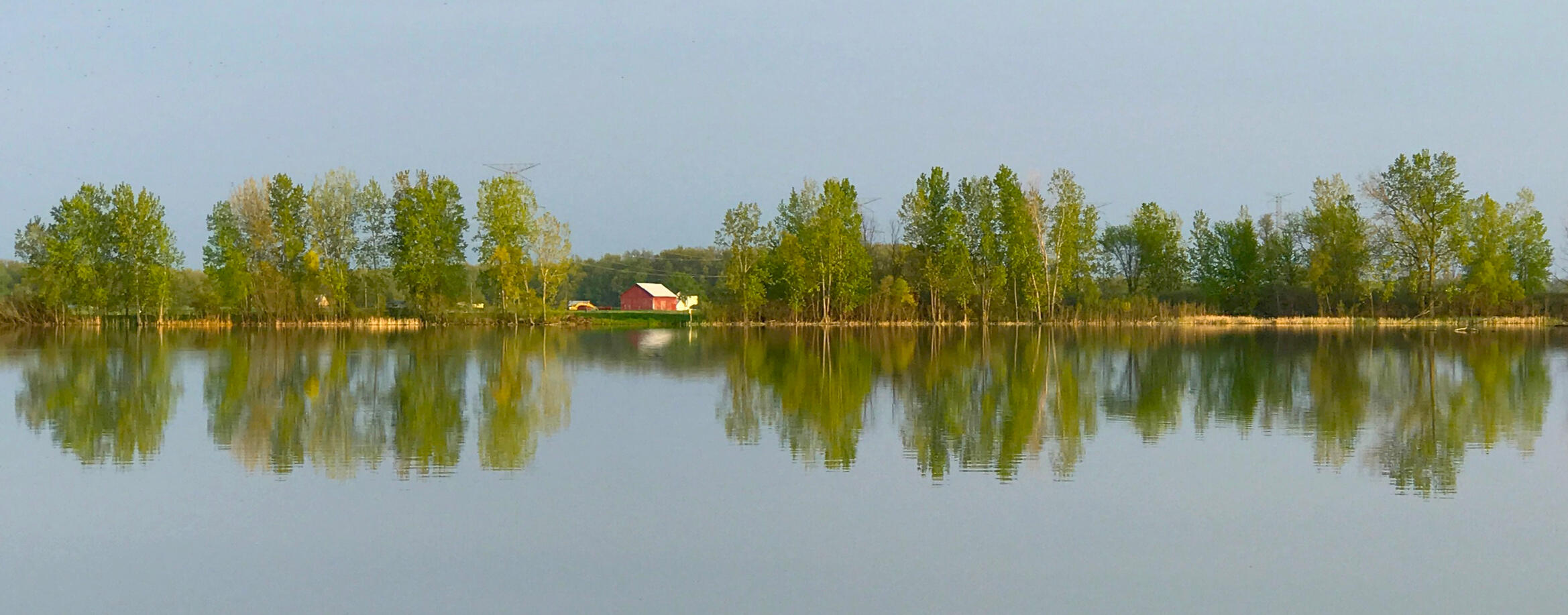 Wide format rural red barn reflection in river